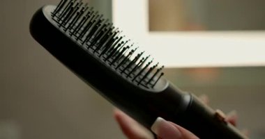 Kadın eli, şık bir banyodaki saç kurutma makinesine başlık takar. Bu görev, günlük bakım rutininin bir parçasıdır. Saç için optimal stil sonuçlarının sağlanmasıdır..
