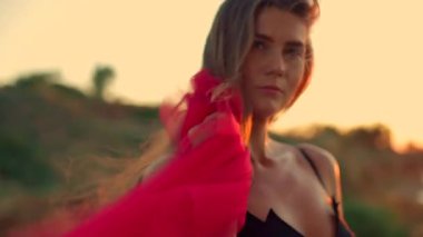 Uzun boylu kız, kumsalda zarif bir şekilde duruyor güneş yükselirken kumların ve suyun üzerinden sıcak altın bir ışık saçıyor. Saçlarını yavaşça hareket ettiriyor ve sakin atmosferi kucaklıyor.