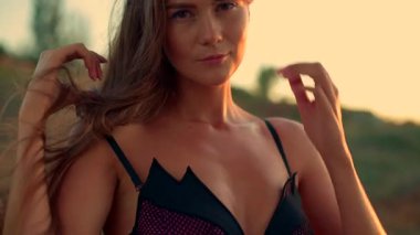 Güzel, uzun boylu bir kız kumsalda güneşin sıcacık parıltısıyla güneşlenirken dalgalar usulca kıyıya vuruyor ve sakin sabahının tadını çıkarıyor.