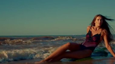 Sabahın erken saatlerinde güzel, uzun boylu bir kız plaj kayasında dinlenir. Güneşinin etrafında dalgalar dolaşır. Huzurlu okyanusu aydınlatır.