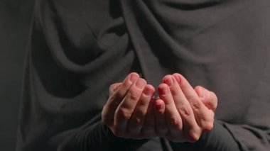 Tesettürlü bir kadın elinde Argan fındıklarını nazikçe tutar. yumuşak ışıklandırma sıcak ve sakinleştirici bir atmosfer yaratarak odaklanmış ifadesini vurguluyor.