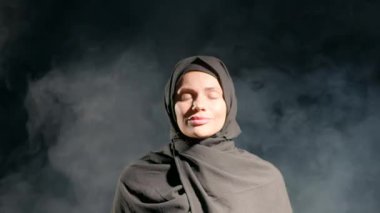 Kadın sakin bir şekilde gözlerini kapatmış tesettüre bürünmüş, sakin ifadesini tamamlıyor. Yumuşak gri duman ruhani bir zemin oluşturur. Anın sükunetini de ekler. Kırmızı gül yaprakları dökülüyor etrafına