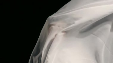 Huzurlu bir anda tesettürlü kadın kültürel mirasını kucaklıyor. Yumuşak kumaş zarif bir şekilde zıtlaşıyor. Güzel, koyu bir arka plan ve onun sessiz gücünü vurguluyor..