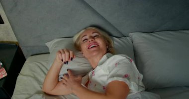 Gecenin geç saatlerinde rahat bir yatak odasında, bir kız telefonda konuşurken gülümseyerek kulaklıklarla yatakta dinleniyor. Rahatlamış tavrı arkadaşça bir konuşma olduğunu gösteriyor..