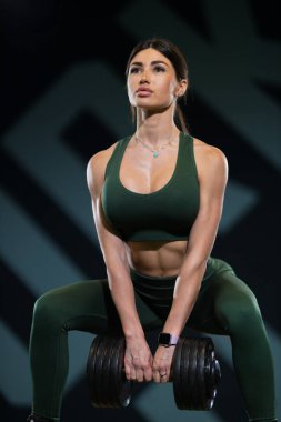 Fitness meraklısı spor salonunda ağır dambılları kaldırırken güç ve kararlılık gösteriyor. Bireyler uyumlu atletizm giysileri giyer ve kaslarını sergiler..