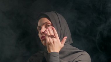 Siyah tesettürlü kadın sakin bir atmosferde nazikçe cilt bakımı yapıyor. yumuşak ışıklandırma onun odaklanmış ifadesini geliştiren sakin bir ortam yaratır..