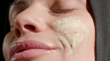 Kadın başörtüsü nazikçe yeşil cilt bakımı uyguluyor. Yüzü aydınlık bir odada. Bağlılığını, özbakımını ve güzellik alışkanlıklarını vurguluyor..