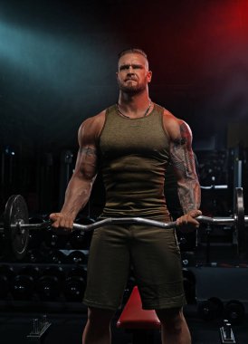 Güçlü bireyler spor salonunda halteri sıkıca kavrayıp güç antrenmanına odaklanırlar. Aydınlatma ağırlıklar kaldırılırken kararlılık ve uygunluğu vurguluyor.