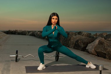 Fitness meraklısı bir sonraki sahil günbatımında mindere hamle yapacak. Sakin su ve kayalar egzersiz için sakin bir zemin sağlar.