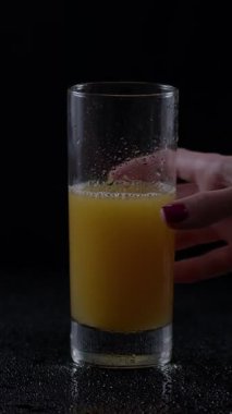 Cilalanmış tırnakları olan el taze sıkılmış portakal suyuyla dolu uzun bir bardağı nazikçe kavrıyor. Bardaktaki buğulanma serinletici içeceği vurguluyor sıcak bir öğleden sonra için mükemmel..