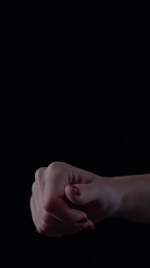 Nazikçe hazırlanmış, zarif ve klas bir şekilde siyah bir arkaplana karşı duran bir kadın eli. Işıklandırma hassas özellikleri ve zarif duruşu vurguluyor..