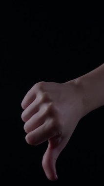 Loş bir ışıkta, bir kadının elini aşağı doğru bir pozisyona indirir ve sonra karşıt duygular taşıyan baş parmaklar yukarı kaldırır..