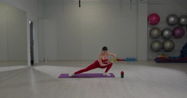 Aydınlık ve ferah bir spor salonunda spor aletleriyle antrenman yapmak. Alt vücut egzersizleri için uygun teknik ve forma odaklanılır..