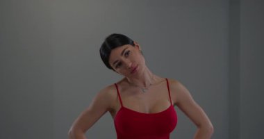 Minimalist bir kapalı mekan ortamında kız boynunu zarifçe uzatıyor. Yumuşak gri arka plan, sakin ve düşünceli bir anı somutlaştıran esneklik ve vücut farkındalığı üzerine yoğunlaşmasını tamamlıyor..