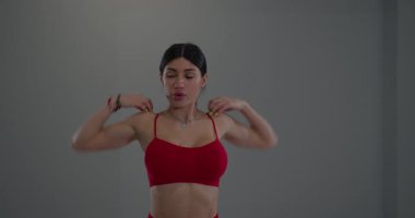 Kararlı bir ifadeyle kız geniş bir spor salonunda omuz geriyor. Esneklik rutinine girerken, parlak ortam onun dikkatini arttırıyor..