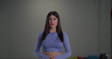 Sportif bir kız spiker, iyi aydınlatılmış kapalı bir mekanda yaklaşan atletik etkinlik için heyecanını yansıtırken kameraya bağlanıyor. Kendine güveni ve enerjisi var..