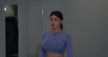 Atletik kız sola ve sağa eğiliyor esnekliğini ve gücünü geliştirmeye odaklanıyor. Spor salonu spor salonunda spor salonuna kendini spora adadı..