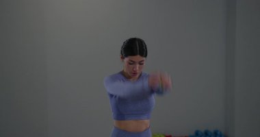 Genç atletik kız, geniş bir spor salonunda kollarını ileri geri sallayarak enerjik bir egzersiz yapıyor. Ayarlar fitness ve hareketi teşvik eder..
