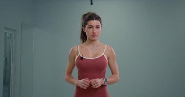 Sportif kız spiker güvenle kameraya doğru konuşuyor. Modern bir jimnastik salonunda spor yaparken coşkuyla spor yapmayı destekliyor..