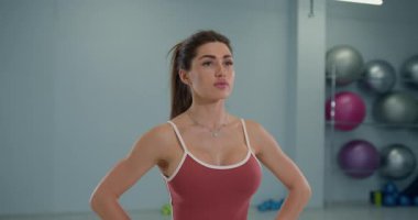 Geniş bir eğitim tesisinde bir kız sporcu spor rutininin bir parçası olarak başını sağa ve sola eğiyor. Dengelemeye ve koordinasyonunu geliştirmeye odaklanıyor..
