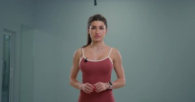 Sportif kız, kapalı mekan ortamında kameraya çekici bir duyuru yapıyor. Kendine güveni ve odaklanmış ifadesi, yaklaşan olaya duyduğu heyecanı vurguluyor..