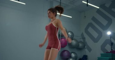 Genç bayan sporcu modern bir spor salonundaki egzersiz rutinine odaklanarak atlama hareketleri yapıyor..