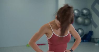 Kız sporcu, koordinasyon ve dengesini geliştirmek için dairesel bir hareketle kafa döndürme işlemi yapıyor. Egzersiz malzemeleriyle dolu bir eğitim stüdyosuna odaklanmış durumda..