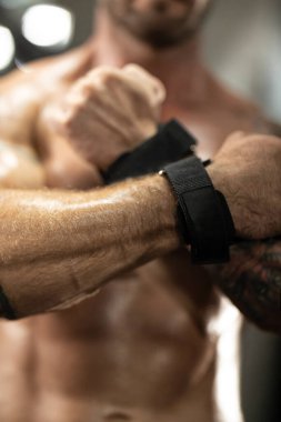 Güçlü kollar, iyi donanımlı bir spor salonunda ağırlık kaldırma seansına hazırlanıyor. Bireysel olarak siyah bileklikleri sıkıca tutar ve desteğini arttırır..