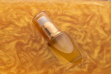 Sarı parfüm şişesi altın suya batırılır ve ışığı güzel yansıtır. Etrafındaki yumuşak dalgalar şatafatlı hissi artırıyor. Bu da onu parfüm severler için davetkar bir sahne yapıyor..