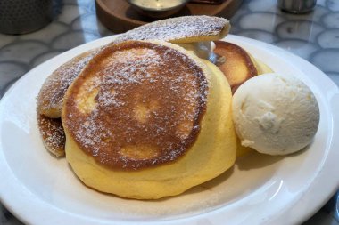 Lezzetli Japon pofuduk krep tatlısını vanilyalı dondurma ve beyaz tabakta servis edilen karamelli muzla kapat.