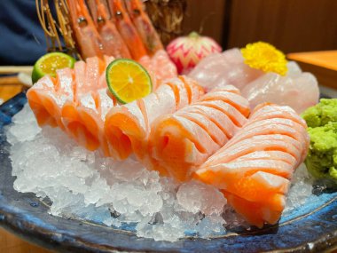 Japon restoranında çeşit çeşit saşimi. Taze somon, karides, tabak süslemeli Kanpachi. Somon dilimlerine odaklan..