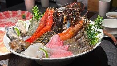 Istakoz, farklı türde karides, istiridye, balık, istiridye, deniz tarağı ve kalamar içeren büyük beyaz tabak üzerine servis edilen çeşitli deniz ürünleri tabağı. Yakın çekim.