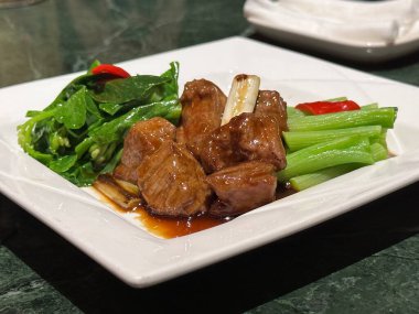 Sos ve sebzeli sarımsak küpleri beyaz tabakta, Asya yemeği, et güveci, soslu gulaş, yakın plan..