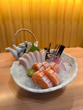 Yakın plan Sashimi, somon balığı ve arka planda çaydanlık bulunan Kılıçbalığı göbeği. Üst görünüm