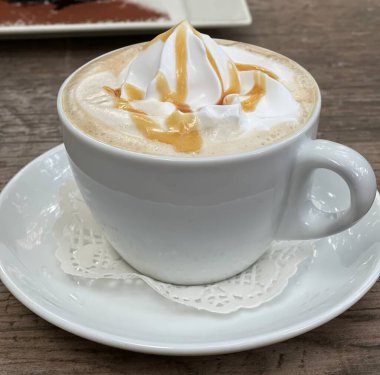 Tahta masanın üzerinde krem şantili karamel latte.