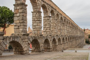 İspanya 'daki Segovia' nın Roma su kemeri manzarası. Sütunların arasında bir katedral var.