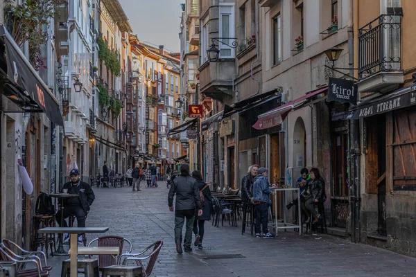 Vitoria-Gasteiz, İspanya - 26 Mart 2023: İnsanlar renkli bir sokakta balkonlarında çiçeklerle içki içmekten keyif alıyorlar