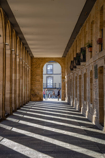 Vitoria-Gasteiz, Spain - 26 March 2023: People entering Los Arquillos, the historical passage, shadows on the floor
