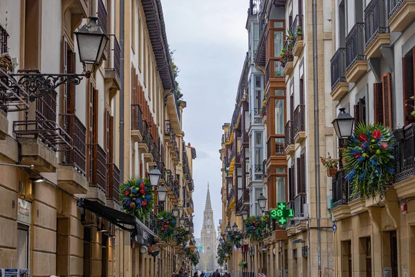 San Sebastian, İspanya - 31 Mart 2023 Balkonlarda çiçekler ve katedral manzaralı güzel bir cadde