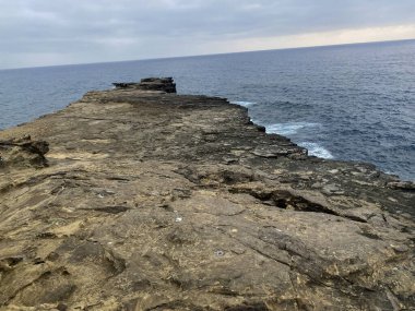Kaya oluşumu, okyanusun ufkuna uzanan eski bir yol gibi uzanıyor..