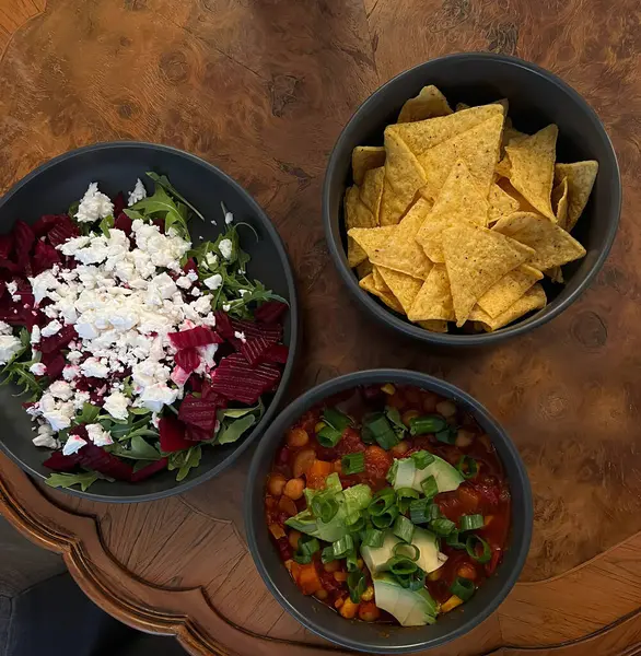 Bir tanesinde çiğ pancar ve peynir salatası, diğerinde domates soslu baharatlı fasulye ve karışık sebzeler, üçüncüsünde tortilla cipsi, üst görünümde