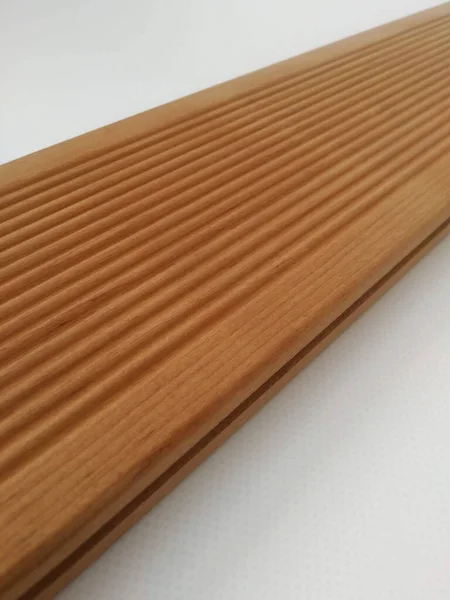 Terrace thermal board made of light brown ash with a ribbed surface. Wooden background with wood texture.