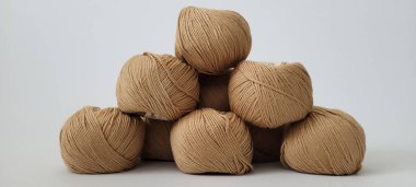 Beyaz arka planda bir piramide serilmiş bej örgü ipliği. Beyaz arka planda akrilik ve pamuk liflerinin karışımından yapılmış bir sürü bej iplik. Örgü örmek ya da tarafsız bej rengi örmek için iğrenç bir yol.