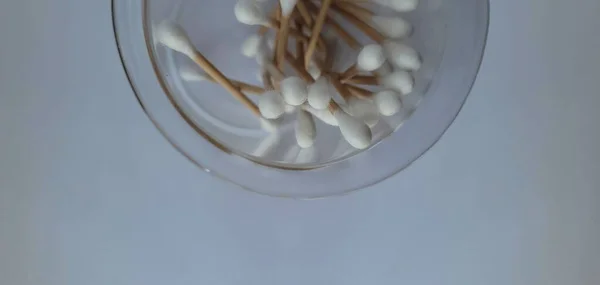 Beyaz arkaplanda cam bir kavanozdaki bambu pamuk örneklerinin yakın plan görüntüsü.. 