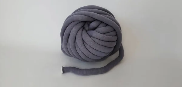 Chunky cotton yarn was made from organic cotton and inside tube filling is polyester. Big gray yarn on white background. No stitch on the size, continuous tube yarn.