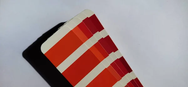 Pantone Renk Eşleştirme Sistemi. Beyaz arka planda kırmızı palet. Renk oluşturma sistemi, beyaz arkaplanda kırmızı ve pembe renk tonlarına sahip bir yelpaze.