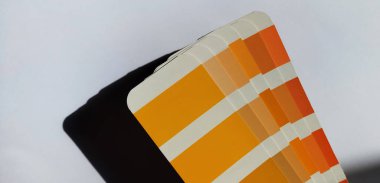 Pantone Renk Eşleştirme Sistemi. Beyaz arka planda turuncu palet. Renk oluşturma sistemi, beyaz arkaplanda turuncu renk tonlarına sahip bir yelpaze.