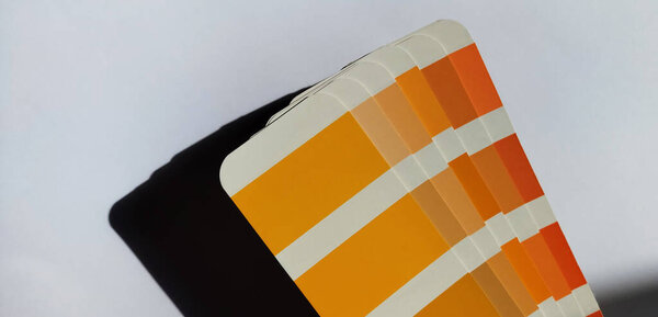 Pantone Color Matching System. Orange palette on a white background. Color rendering system, a fan with swatches of shades of orange colors on a white background.