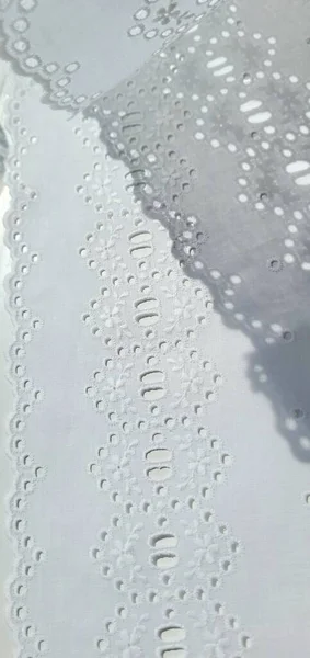 Delinmiş beyaz pamuk kumaş ve nakışlı çiçekler karmaşık ve hassas bir tasarım..