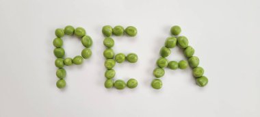 Bezelye kelimesi beyaz arka plandaki bezelyelerden oluşur. Genç bezelyelerle patlayan taze, canlı bezelye kabuklarının yakın çekimi, beyaz arka planda güzelce düzenlenmiş. Bu hassas ve besleyici baklagiller gerçek bir yaz sevinci.